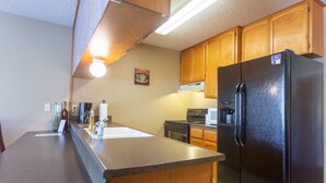 A kitchen with wooden cabinets, a black refrigerator, a stove, and a microwave.