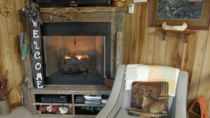 A cozy living room with a fireplace, a sofa with a cheetah pillow, and a 'WELCOME' sign.