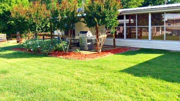 A residential property with a well-maintained lawn, a patio area, and a large windowed structure.