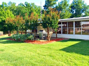 A residential property with a well-maintained lawn, a patio area, and a large windowed structure. - Lodging on Reelfoot Lake Upper Blue Basin at The Bayou Bungalow (Union City)