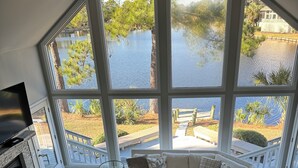 Ein geräumiges Wohnzimmer mit großem Fenster mit Seeblick, einem Kamin und einer gemütlichen Sitzecke.