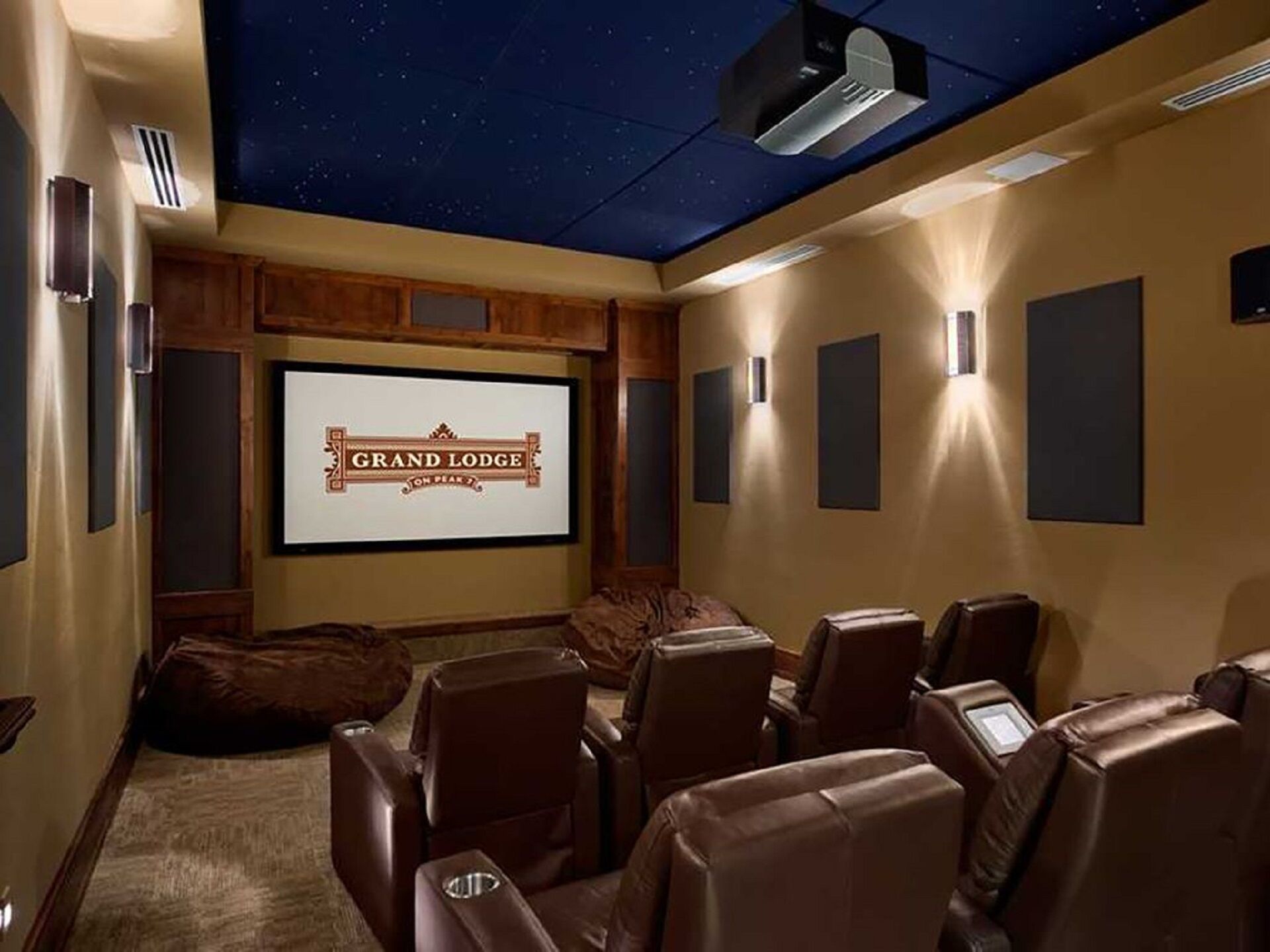 Un cine en casa con techo estrellado, una pantalla grande mostrando 