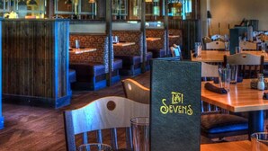 Ein Restaurantinneres mit Sitzboxen, Tischen, hängenden Pendelleuchten und einer sichtbaren Speisekarte.