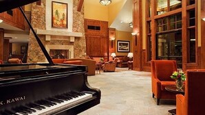 Ein Flügel in einer geräumigen Lobby mit Steinwänden, Holzbalken und großen Fenstern.
