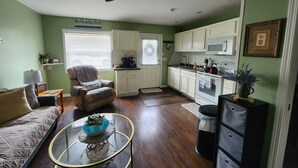 A living room with a sofa, a glass coffee table, a chair, and a ceiling fan.