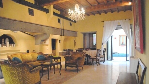 A spacious living room with a high ceiling, a chandelier, and a dining area with a table and chairs.