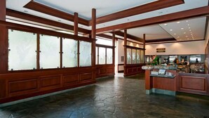 A spacious lobby with wooden beams, large windows, and a reception desk.