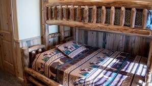 A rustic wooden bed with a patterned bedspread and a headboard with vertical slats.