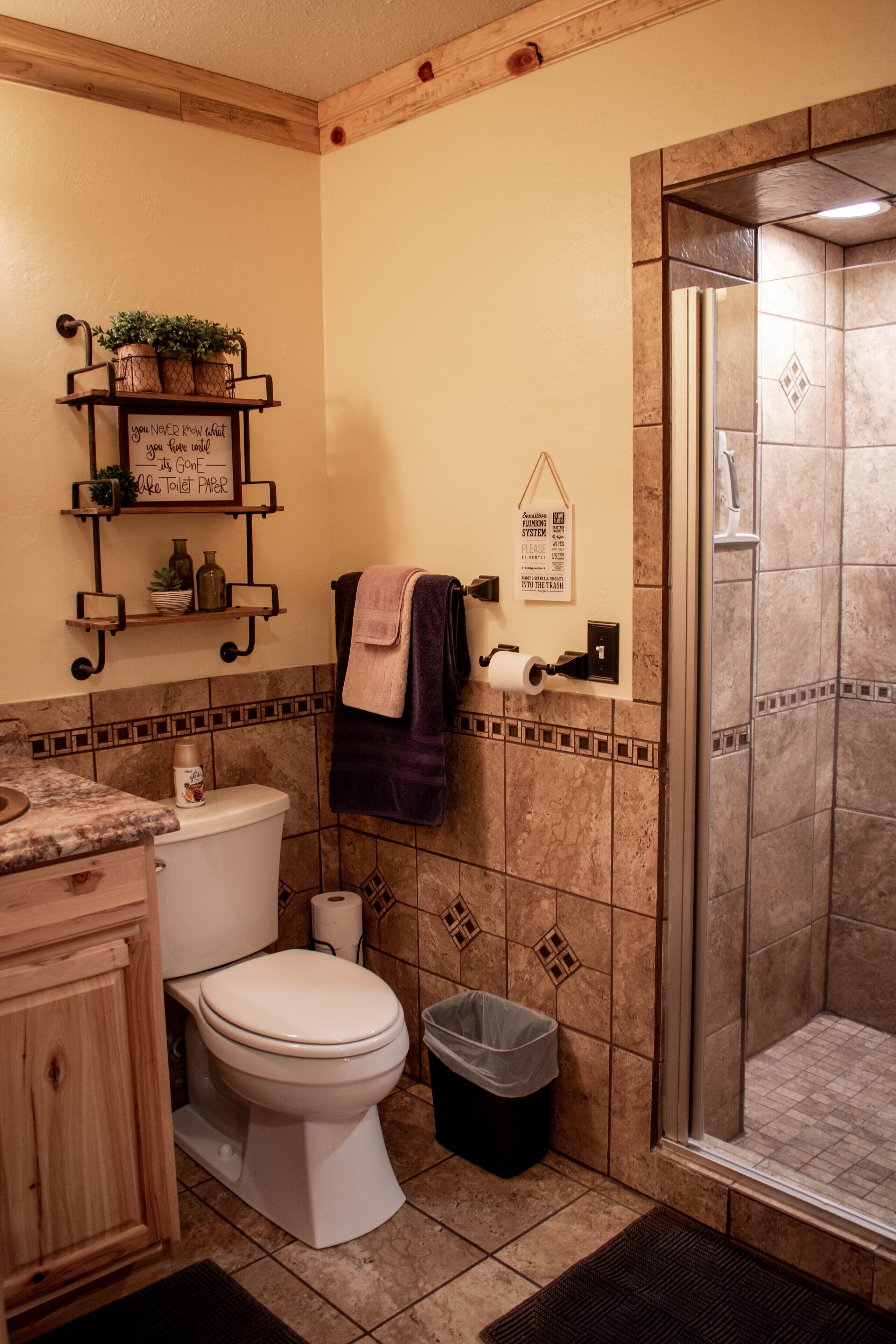 Une salle de bain équipée de toilettes, d’une douche et d’une étagère où sont rangés les articles de toilette.