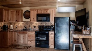 A kitchen with wooden cabinets, a black refrigerator, a microwave, and a stove.