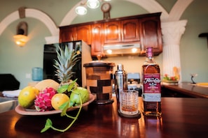 Una encimera de cocina con una botella de Ron de Canela, un vaso y un plato de frutas.