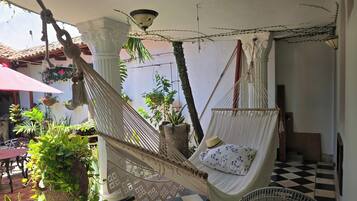 Una silla hamaca con cojín, un adorno colgante de macramé y plantas en macetas.