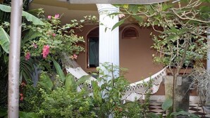 A hammock in a lush garden with a building in the background. - Casa Don Carlos a Gorgeous Colonial House! (Granada)