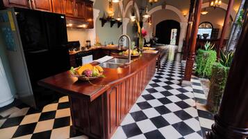 Una cocina con piso a cuadros, armarios de madera y una isla central con frutas y verduras.