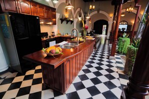 Una cocina con piso a cuadros, armarios de madera y una isla central con frutas y verduras.