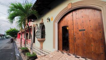 Un edificio con una puerta de madera grande, piso a cuadros y una palmera.
