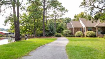 A residential property with a paved driveway leading to a house with a stone foundation and a gabled roof.