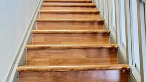 Eine Holztreppe mit weißen Geländern und einem gerahmten Bild oben.