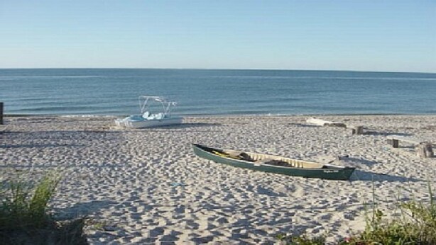 Une plage avec un bateau à rames et un petit bateau sur le sable.
