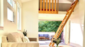 Een moderne woonkamer met een bank, salontafel en een houten trap naar een verdieping erboven.
