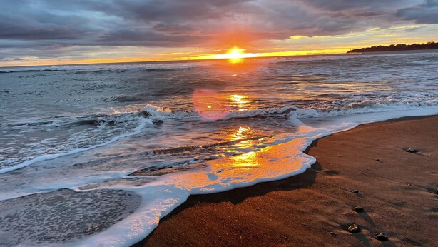 Een strand met golven en een zonsondergang.