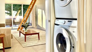 Een moderne wasruimte met een voorlader wasmachine en droger, een houten trap en uitzicht op de omgeving.