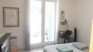 A hotel room with a bed, a desk, a chair, and a window with a view of the outside.