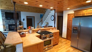 A modern kitchen with wooden cabinets, a stainless steel refrigerator, a built-in oven, and a large island with a kettle. - Exceptional Chalet near Harbor, Nubs Nob and Boyne Highlands Ski and Golf Resort (Harbor Springs)