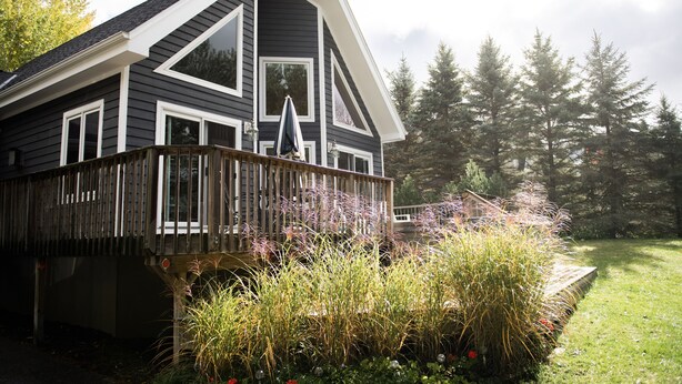 A house with a wooden deck, large windows, and a garden with various plants. - Exceptional Chalet near Harbor, Nubs Nob and Boyne Highlands Ski and Golf Resort (Harbor Springs)