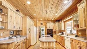 A spacious kitchen with wooden cabinets, a central island, and a built-in oven. - Huge Log Cabin on 20 Acre Ranch close to Grand Canyon with Spectacular Views! (Williams)