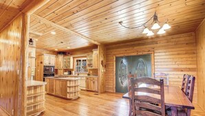 A wooden cabin interior with a kitchen, dining area, and a large wooden door. - Huge Log Cabin on 20 Acre Ranch close to Grand Canyon with Spectacular Views! (Williams)