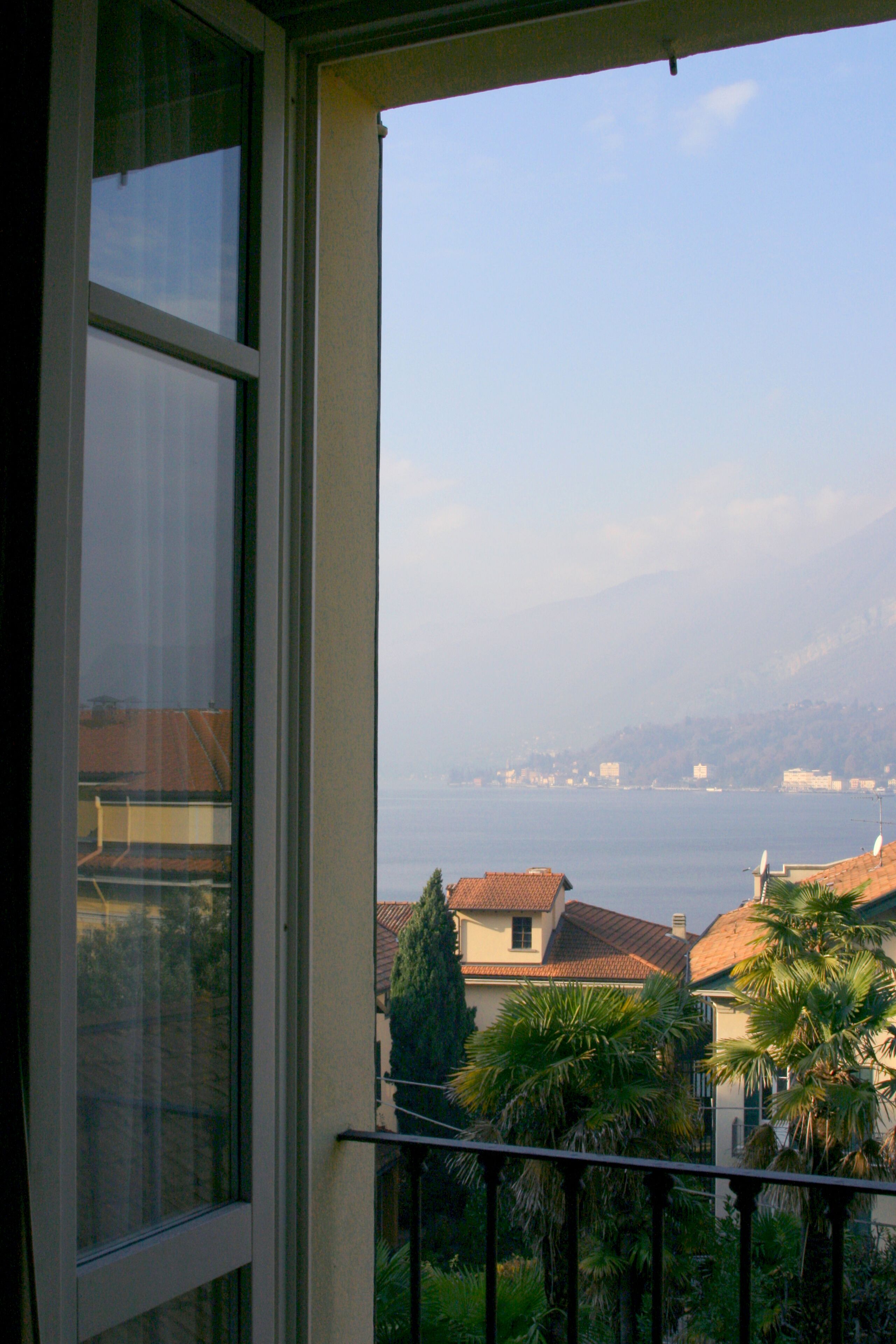 Un balcone con vista su un lago e edifici in lontananza.