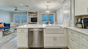 A modern kitchen with white cabinetry, a dishwasher, and a dining area with a white table and chairs.