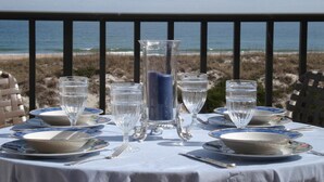 A table set for dining with a view of the beach and ocean.