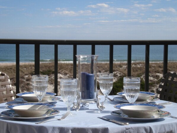 A table set for dining with a view of the beach and ocean.