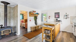 A cozy kitchen with a wood stove, a wooden bench, and a breakfast bar.