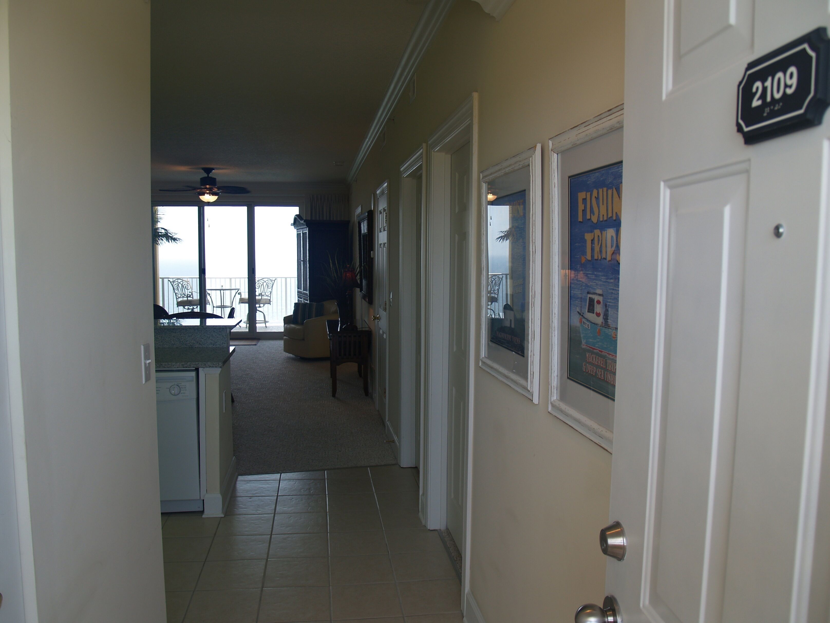 A hallway leading to a balcony with a view, a door labeled 2109, and a poster advertising fishing trips.