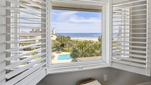 Ein Zimmer mit großem Fenster, Blick auf Pool und Strand.