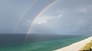 Una playa con un arcoíris sobre el océano y un cielo despejado.