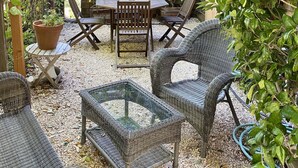 Een terras met wicker meubels, een ronde tafel en stoelen.