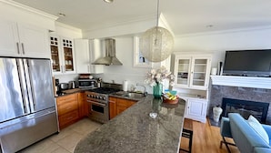 Een moderne keuken met roestvrijstalen apparatuur, een granieten aanrechtblad en een groot eiland.