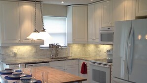 A modern kitchen with white cabinets, a wooden island, a stainless steel refrigerator, and a microwave. - No snow here. 5 minute walk to the beach. Quiet neighborhood. (Ormond Beach)