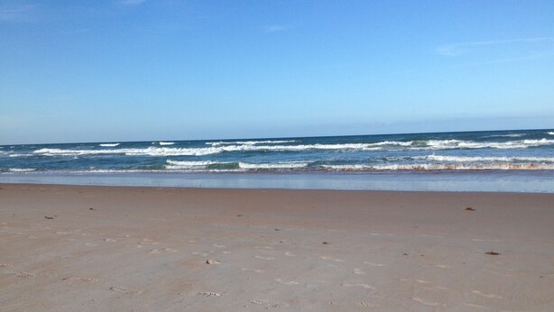 A beach with a clear sky and waves approaching the shore. - No snow here. 5 minute walk to the beach. Quiet neighborhood. (Ormond Beach)