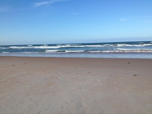 A beach with a clear sky and waves approaching the shore. - No snow here. 5 minute walk to the beach. Quiet neighborhood. (Ormond Beach)