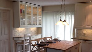 A kitchen with a wooden island, white cabinets, and a hanging light fixture. - No snow here. 5 minute walk to the beach. Quiet neighborhood. (Ormond Beach)