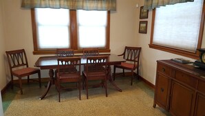 A dining room with a wooden table and chairs, a window with blinds, and a wooden cabinet.