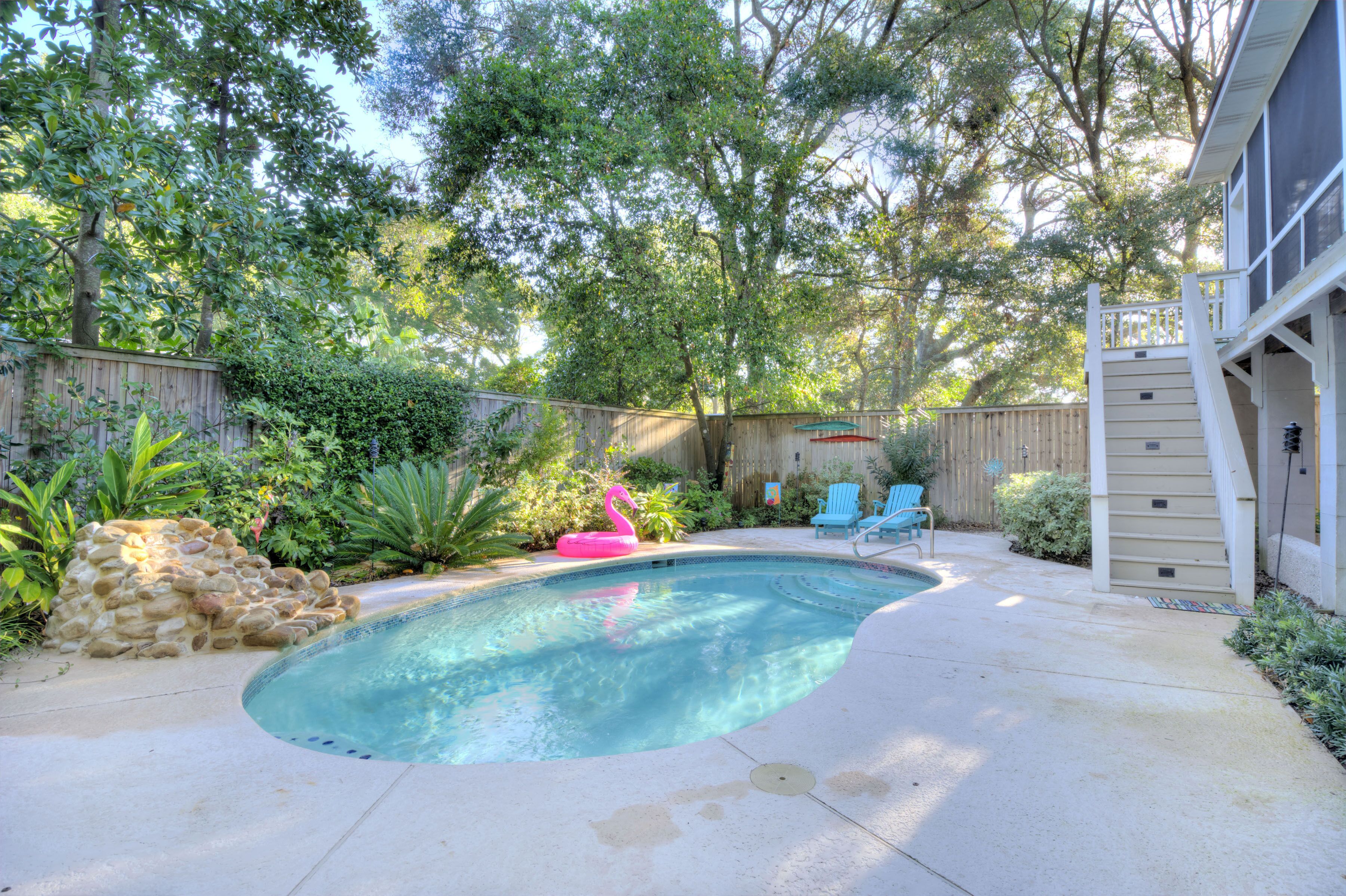 A backyard with a swimming pool, a wooden deck, and a wooden fence.