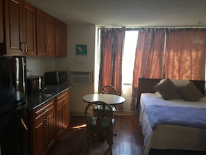 Une petite chambre comprenant un lit, une petite table et un coin cuisine.