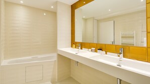 Ein modernes Badezimmer mit einer Badewanne, zwei Waschbecken und einem großen Spiegel.