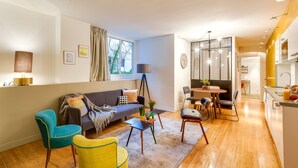 Ein modernes Wohnzimmer mit einer Couch, Sesseln, einem Couchtisch und einem Essbereich mit Tisch und Stühlen.